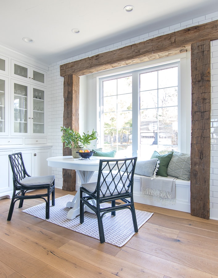 White breakfast nook with rustic beams and green pillows